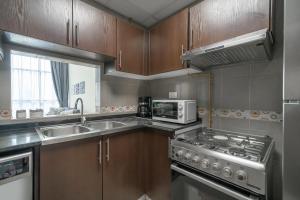 a kitchen with a stove and a sink and a microwave at HiGuests - Oudah Tower in Dubai