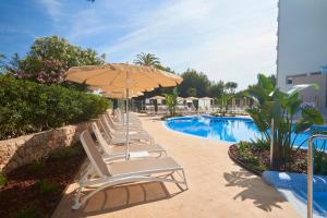 
a patio area with chairs, tables and umbrellas at Hipotels Bahia Cala Millor in Cala Millor
