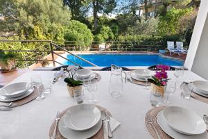 a white table with plates and glasses and a pool at Casa del Capitán in Santa Ponsa