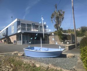 un barco sentado en el suelo frente a una casa en Barracuda, Beachside Apartment en Benllech