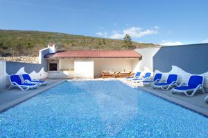a swimming pool with blue chairs and a table at VILLA STARS HILL WITH HEATING POOL and JACUZZI - MAKARSKA in Slivno