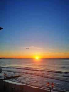 una puesta de sol en la playa con un pájaro volando sobre el océano en B&B DaGiueli, en Alassio