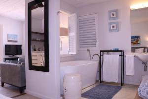 un bagno con vasca, lavandino e specchio di Dune Ridge Cottage a Paternoster