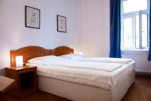 a bedroom with a large white bed and a window at Vila Josefina in Prague