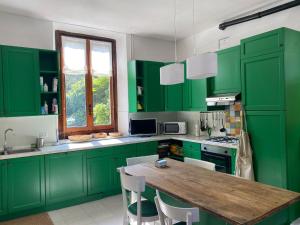 a kitchen with green cabinets and a wooden table at Villino Tarlarini in Laveno-Mombello