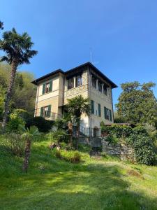 a large house on a hill with a palm tree at Villino Tarlarini in Laveno-Mombello