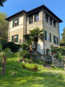 a large house with a palm tree in front of it at Villino Tarlarini in Laveno-Mombello