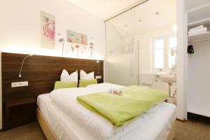 a bedroom with a bed with a green blanket on it at Velden24 - create your own stay in Velden am Wörthersee