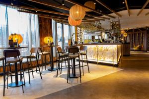 a bar with stools in a room with windows at Fletcher Hotel-Restaurant ByZoo Emmen in Emmen
