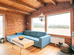 ein Wohnzimmer mit einem blauen Sofa und einem Tisch in der Unterkunft 6 person holiday home in L kken in Løkken