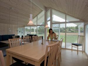 a woman sitting at a table in a dining room at 10 person holiday home in R dby in Kramnitse