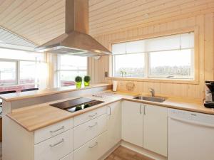 una cocina con armarios blancos, fregadero y ventanas en 6 person holiday home in Tranek r, en Fæbæk