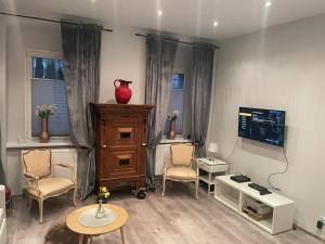 een woonkamer met een tv en een tafel en stoelen bij Apartment Chorzow Center in Chorzów