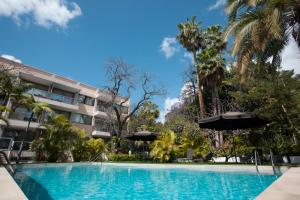 a swimming pool with umbrellas in front of a building at Hotel Colon Rambla in Santa Cruz de Tenerife