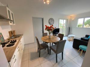 a kitchen and living room with a table with a vase of flowers at Cocooning in Torreilles