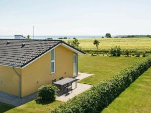 ein gelbes Haus mit einem Picknicktisch neben einem Feld in der Unterkunft 8 person holiday home in Sydals in Mommark