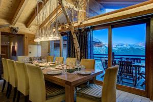 a dining room with a table and chairs and a large window at Chalet Auriane in Riddes