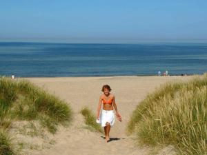 a woman walking on a beach near the ocean at 7 person holiday home in Lemvig in Trans