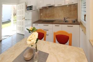 a kitchen with a table, chairs, and a refrigerator at Villas Corinthia in Baška