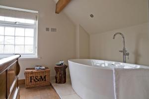 uma grande banheira branca na casa de banho com uma janela em Nether Farm Barns em Ashbourne