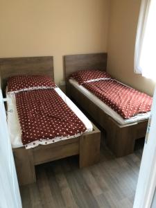 duas camas num pequeno quarto com lençóis vermelhos em Dunasor1 Apartman em Dömsöd