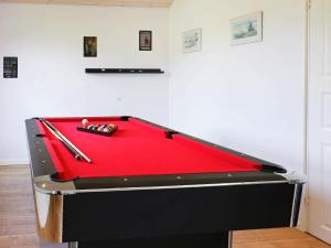 uma mesa de snooker vermelha com dois tacos de bilhar. em 8 person holiday home in Hadsund em Hadsund