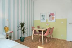 jadalnia ze stołem i różowymi krzesłami w obiekcie Modern 2Br Apartments - Full Kitchen - Schönbrunn Area - 15 Mins to City Center w Wiedniu