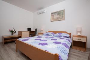 a bedroom with a bed with a purple and white comforter at Apartment Pepi in Lovran