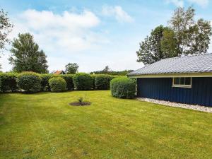 a yard with a blue building and a hedge at 4 person holiday home in Hemmet in Hemmet