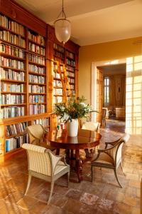 une bibliothèque avec une table, des chaises et des étagères dans l'établissement Hôtel particulier de Tingry - Pierres d'Histoire, à Ménerbes