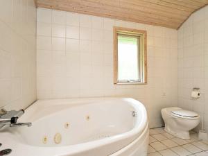 a white bath tub in a bathroom with a toilet at 10 person holiday home in Dannemare in Dannemare