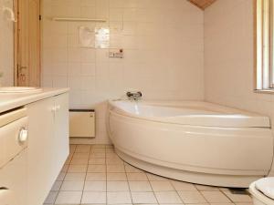 a white bathroom with a tub and a sink at 10 person holiday home in Dannemare in Dannemare
