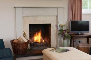 a fireplace in a living room with a fire in it at Braemoray in Evanton