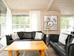 Strandbyにある6 person holiday home in Strandbyのリビングルーム(黒い革張りのソファ、木製テーブル付)