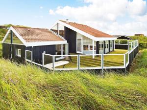 una casa nera con tetto bianco su una spiaggia di Five-Bedroom Holiday home in Løkken 6 a Grønhøj