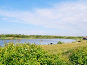 a picnic table sits next to a lake at 6 person holiday home in Ringk bing in Søndervig