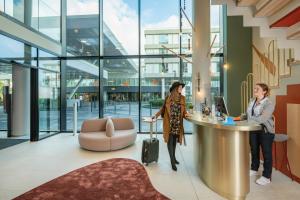 two women standing at a reception desk in a building at Adagio access Brussels Delta in Brussels