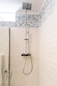 um chuveiro com uma mangueira pendurada no tecto na casa de banho em Dolce vista em Merano