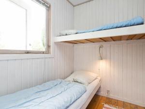 KarrebæksmindeにあるThree-Bedroom Holiday home in Karrebæksminde 1の二段ベッド1組、窓が備わる小さな客室です。
