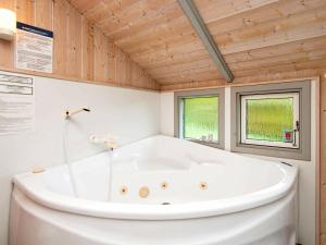 a large white tub in a bathroom with two windows at 6 person holiday home in Sj lund in Sjølund