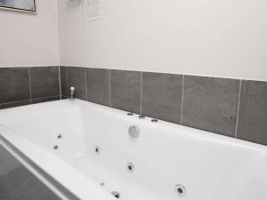 baño con bañera blanca y azulejos grises en 10 person holiday home in Brovst, en Brovst