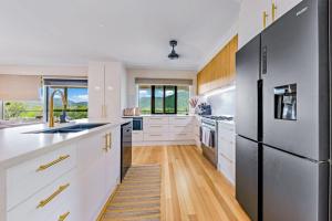 een keuken met witte kasten en een zwarte koelkast bij Airlie Abode in Airlie Beach