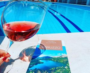 Eine Person, die ein Glas Wein neben einem Buch hält in der Unterkunft Hotel Lady G in Tortoreto Lido
