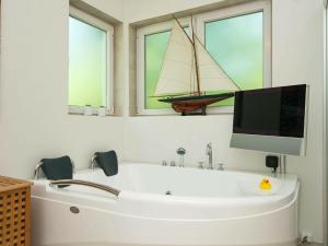 baño con bañera y TV y un barco en la pared en Holiday home Rønde IX, en Rønde