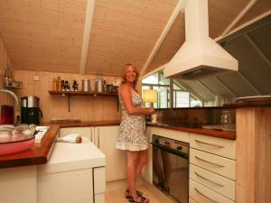 a woman is standing in a kitchen at 6 person holiday home in Dronningm lle in Gilleleje