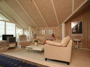 a woman sitting on a couch in a living room at 6 person holiday home in Dronningm lle in Gilleleje