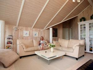 a woman sitting on a couch in a living room at 6 person holiday home in Dronningm lle in Gilleleje