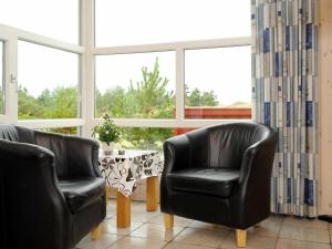 ヘンネ・ストランドにある6 person holiday home in Henneの黒革の椅子2脚、窓際のテーブル