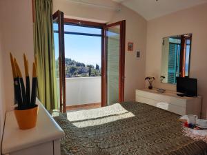 1 dormitorio con 1 cama, TV y ventana en L'Arabesco Apartment, en Amalfi