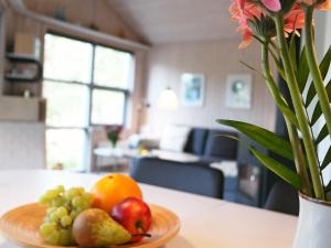 a plate of fruit on a table with a vase of flowers at 6 person holiday home in Fjerritslev in Torup Strand